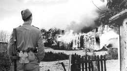 Солдат на фоне горящего дома.